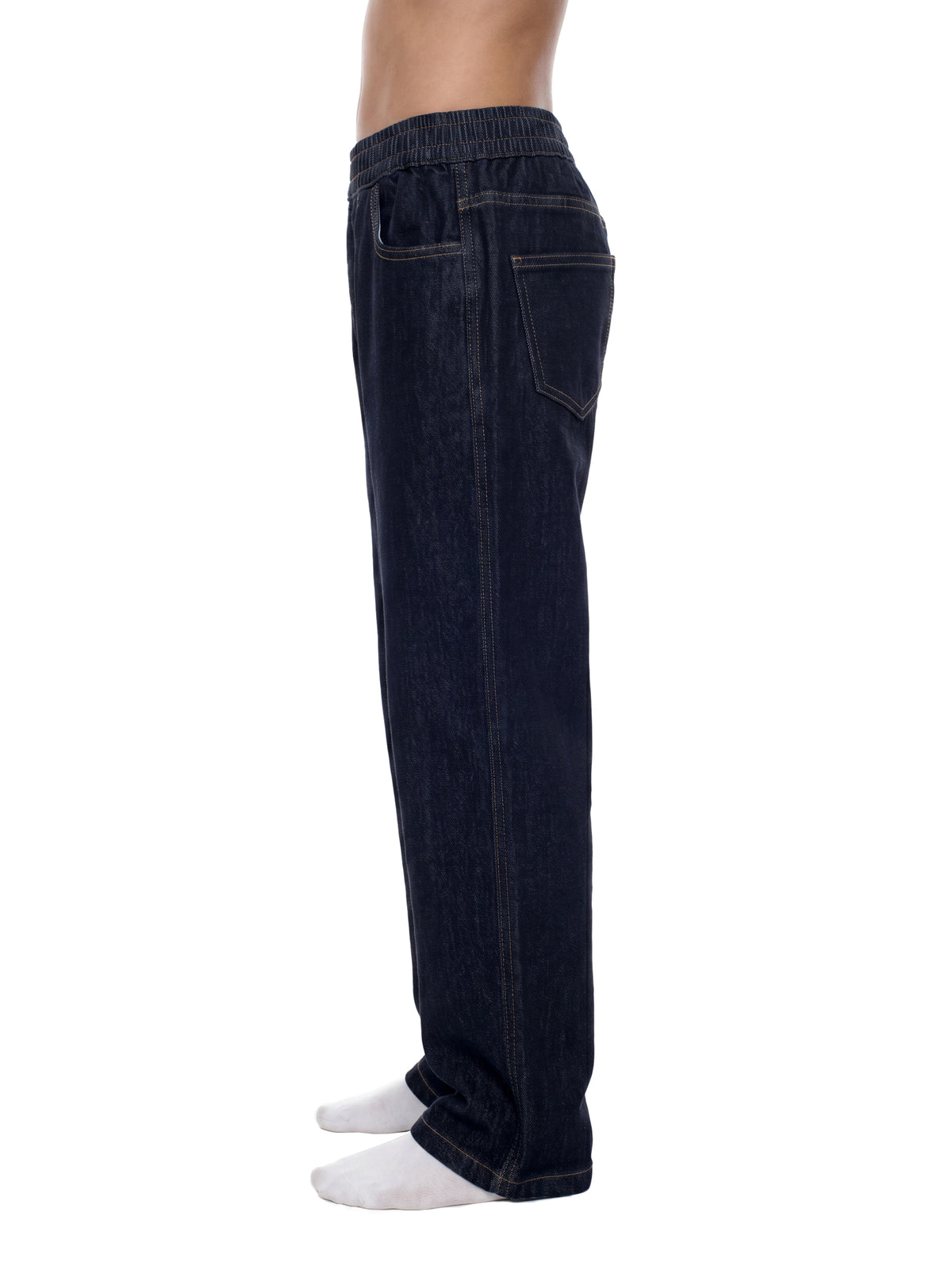 Side view of a person wearing dark indigo denim jogger pants with white socks, shown against a plain white background.