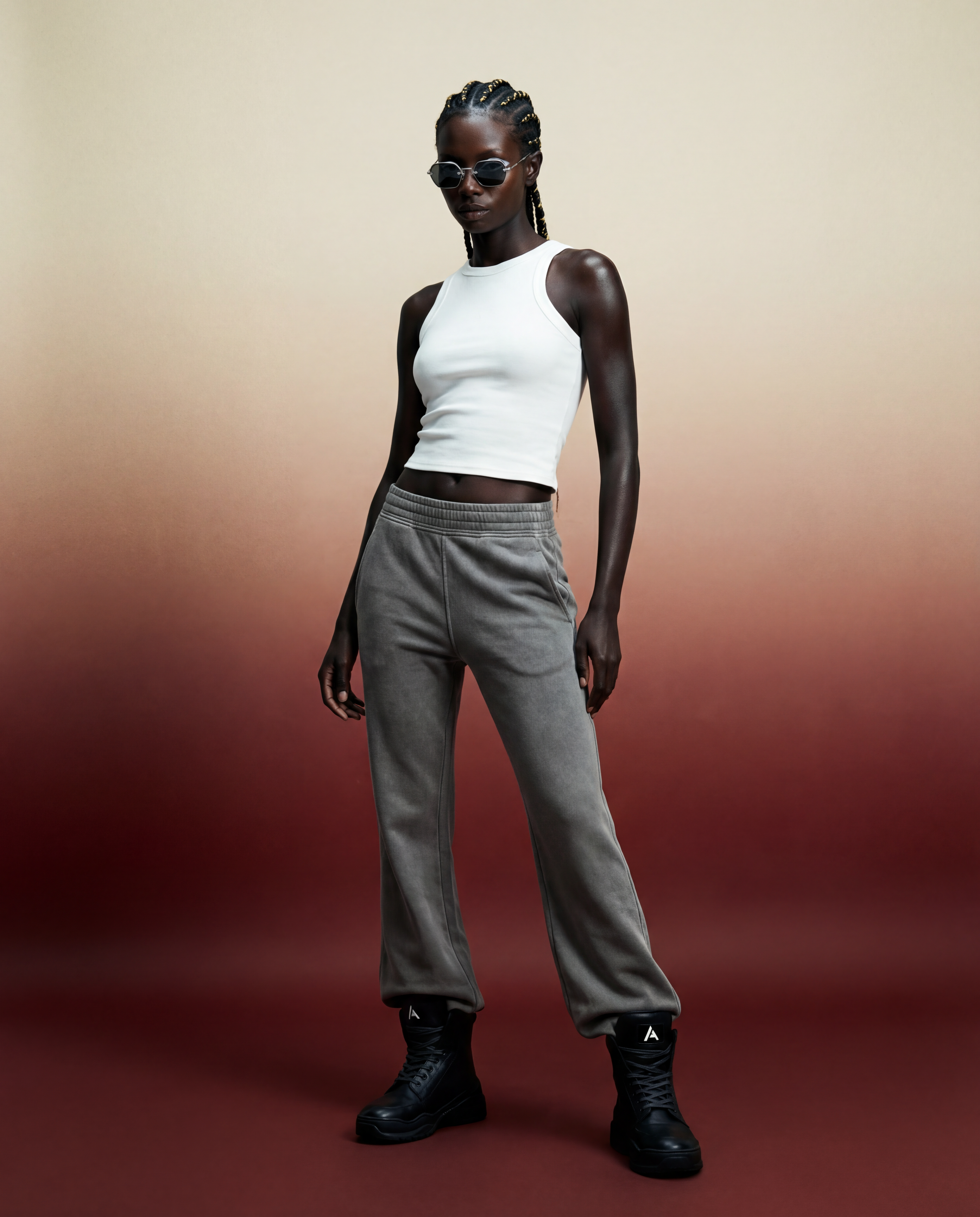 Obsidian-rose concept: Female model wearing a white tank top and gray flared sweats, and arc-ones in the white studio.