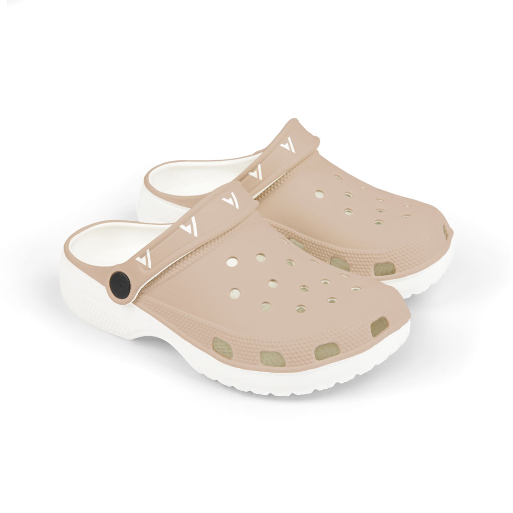 A pair of children's clog-style sandals in a light beige/tan color with a white sole, featuring multiple ventilation holes and a strap with a repeating white V-shaped logo.
