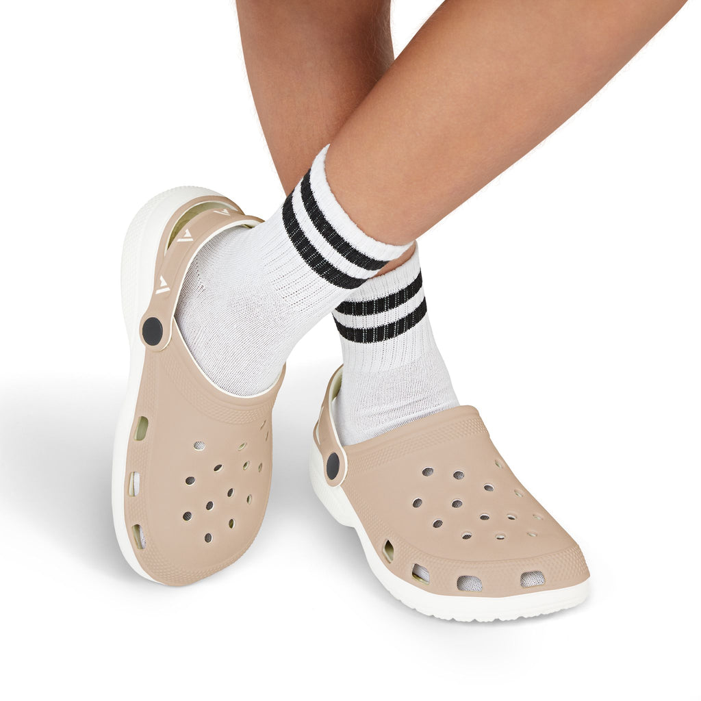 Beige foam clogs with white soles worn with white crew socks featuring black stripes, shown on a person's feet against a white background.